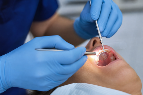 Dentist performing an oral cancer screening exam during a routine dental checkup